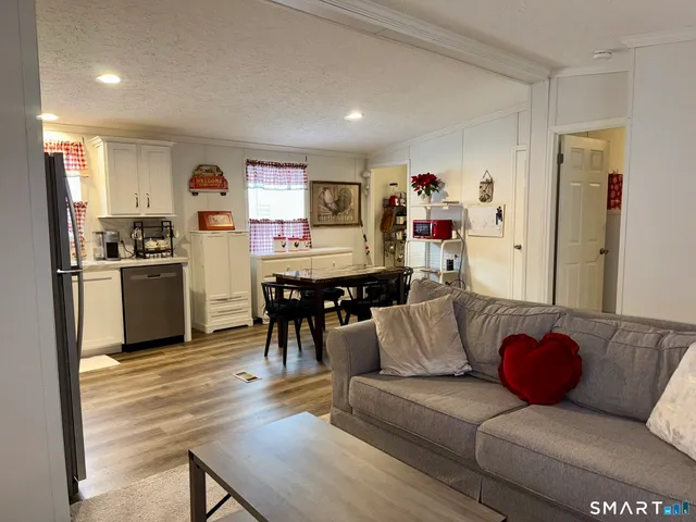 a living room with furniture kitchen view and a wooden floor