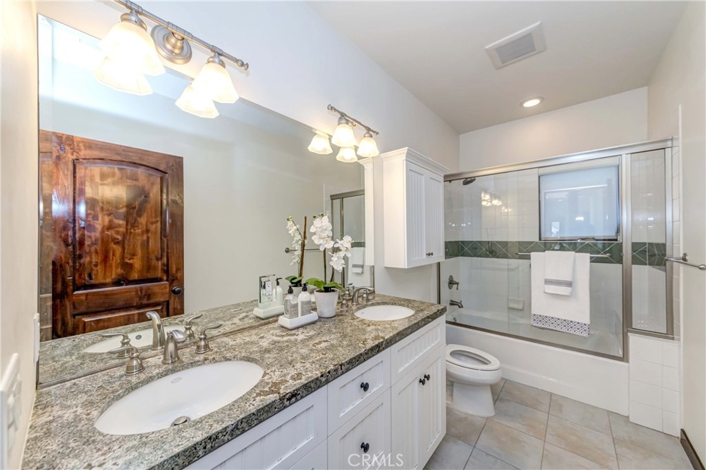 950 Old Mill Road Pasadena, CA 91108 - Photo 30 of 42 a bathroom with a granite countertop sink a toilet a mirror a vanity and shower