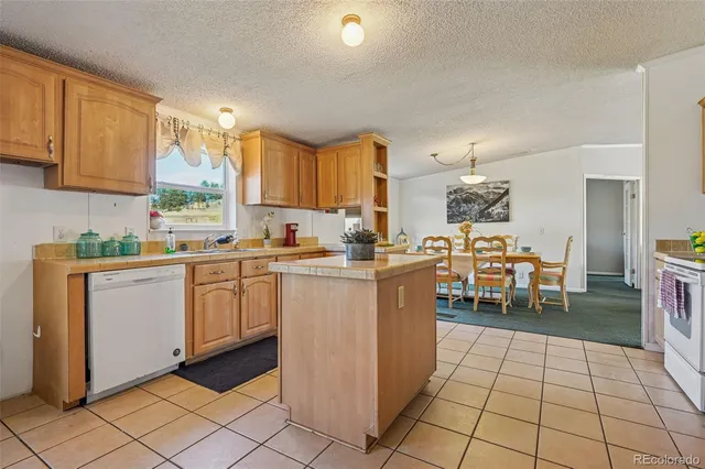 a kitchen with stainless steel appliances granite countertop a refrigerator a sink a stove top oven a dining table and chairs