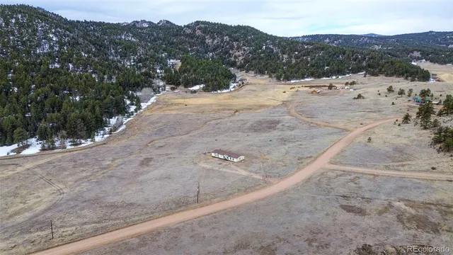 a view of a dry field with mountains in the background