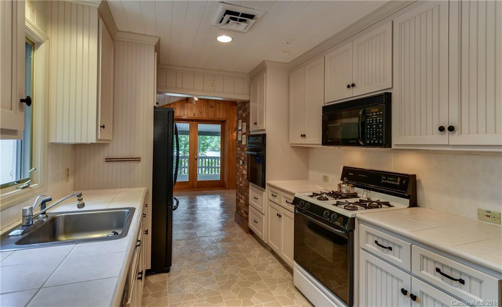 711 Green Hills Road Mill Spring, NC 28756 - Photo 15 of 23 a kitchen with granite countertop a sink a stove and cabinets