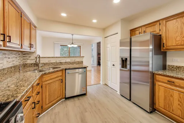 a kitchen with stainless steel appliances granite countertop a refrigerator a sink and white cabinets