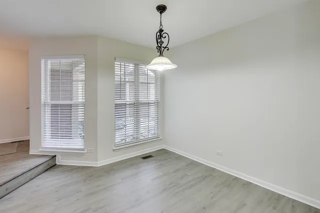 an empty room with wooden floor windows and entrance