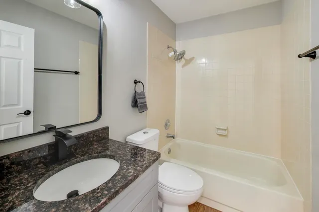 a bathroom with a granite countertop sink toilet and shower