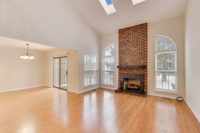 an empty room with windows fireplace and wooden floor