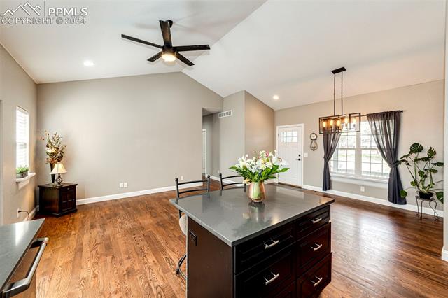 711 Pine Ridge Street Elizabeth, CO 80107 - Photo 19 of 39 Kitchen featuring ceiling fan with notable chandelier, vaulted ceiling, pendant lighting, and dark hardwood / wood-style flooring