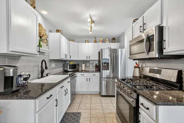 a kitchen with stainless steel appliances granite countertop a sink stove and refrigerator