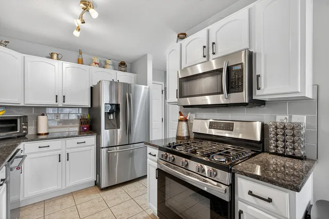 a kitchen with white cabinets and appliances