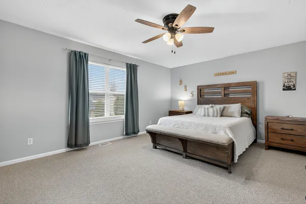 a bedroom with a large bed chandelier and a window