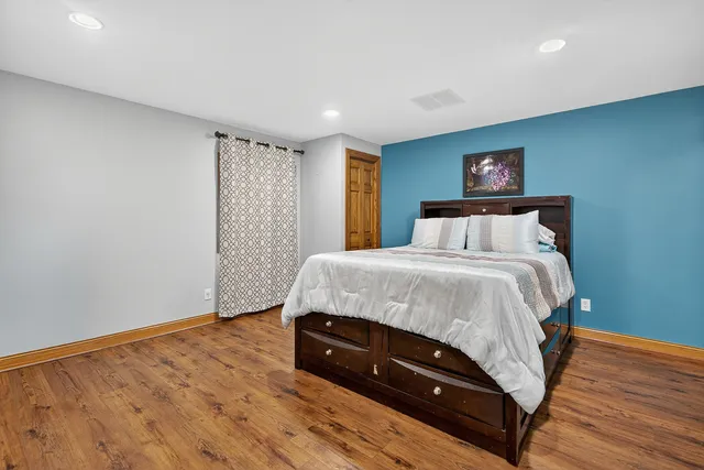 a spacious bedroom with a bed and a painting on the wall