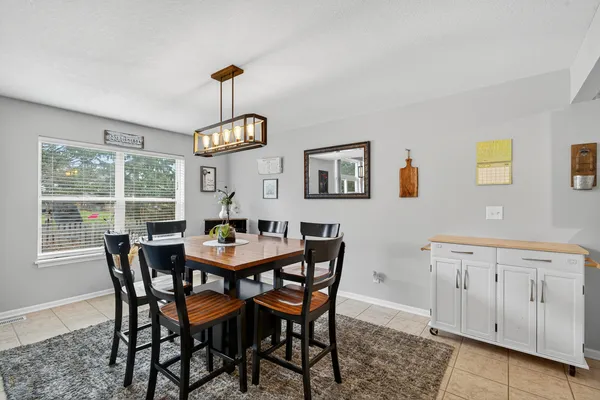 a dining room with wooden floor a chandelier a wooden table and chairs