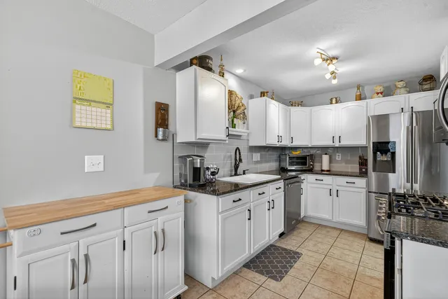 a kitchen with kitchen island granite countertop a sink cabinets stainless steel appliances and a counter top