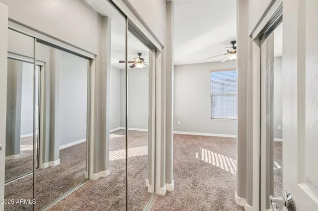 an empty room with a window and chandelier fan