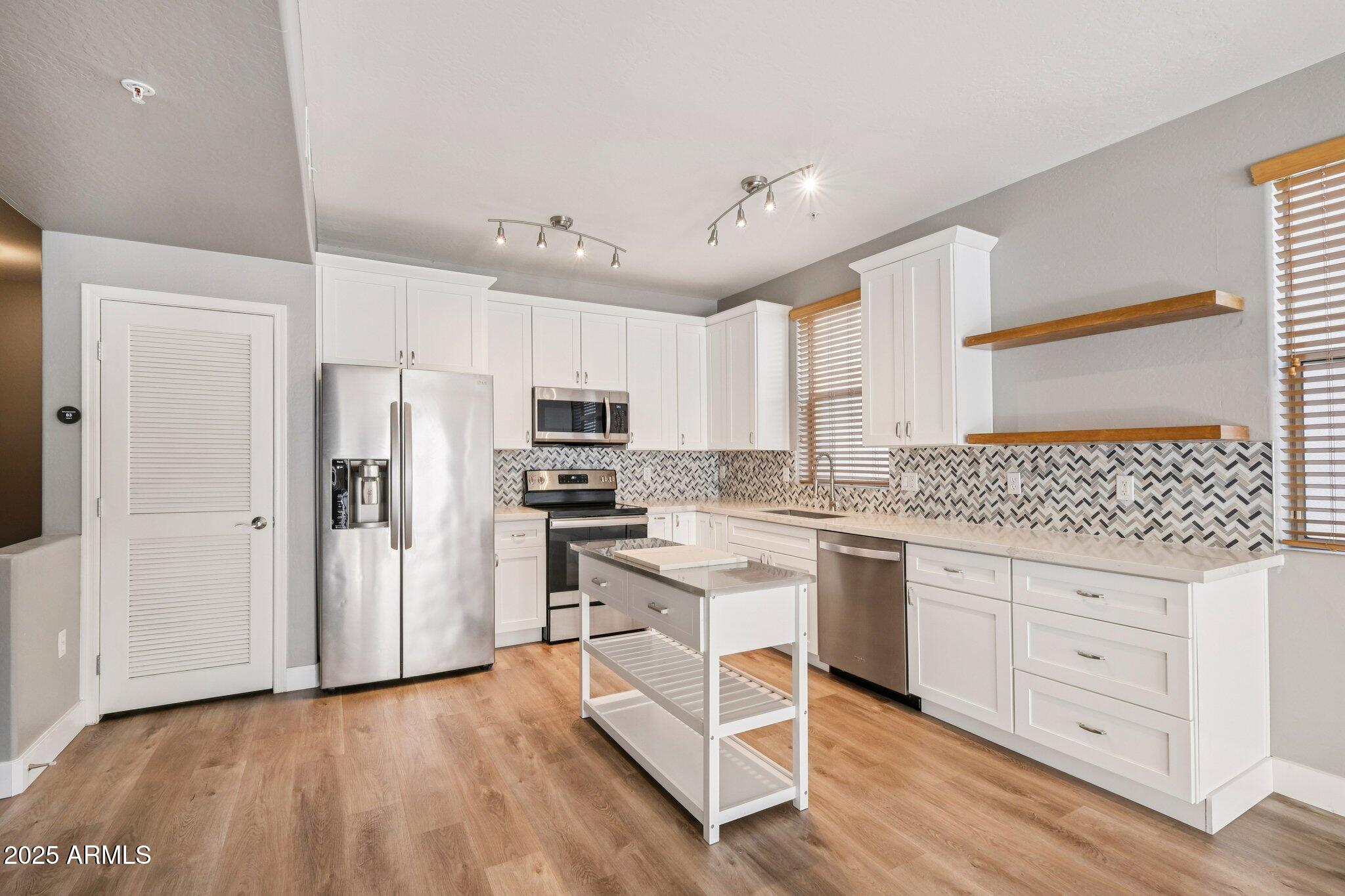 615 East Portland Street, Unit 115 Phoenix, AZ 85004 - Photo 5 of 32 a kitchen with white cabinets and stainless steel appliances