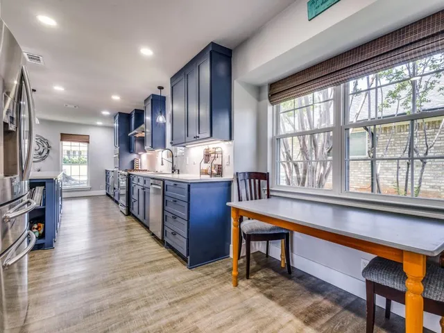 a large kitchen with stainless steel appliances wooden cabinets and a stove top oven