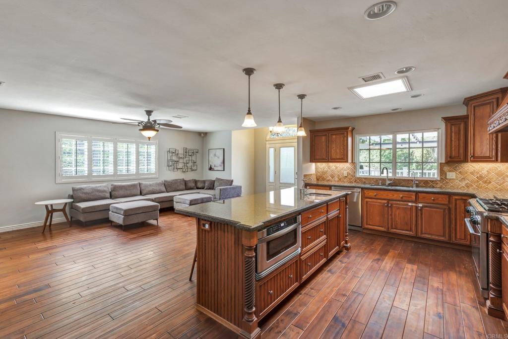 11985 Rocoso Road Lakeside, CA 92040 - Photo 11 of 48 a kitchen with a center island wooden floor and stainless steel appliances