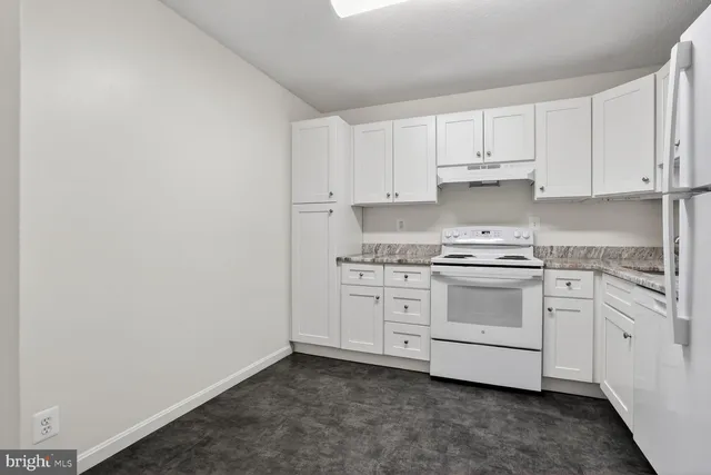 a kitchen with granite countertop white cabinets and white appliances