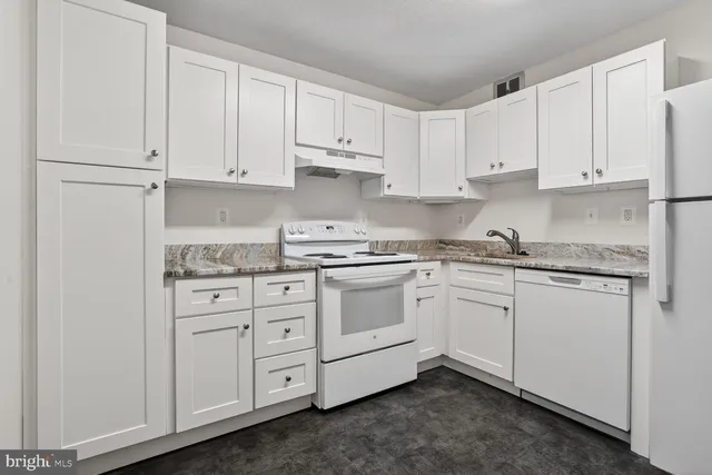 a kitchen with granite countertop white cabinets and white appliances