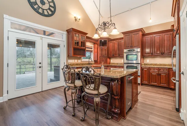 a kitchen with stainless steel appliances granite countertop a refrigerator a oven and a sink with wooden cabinets