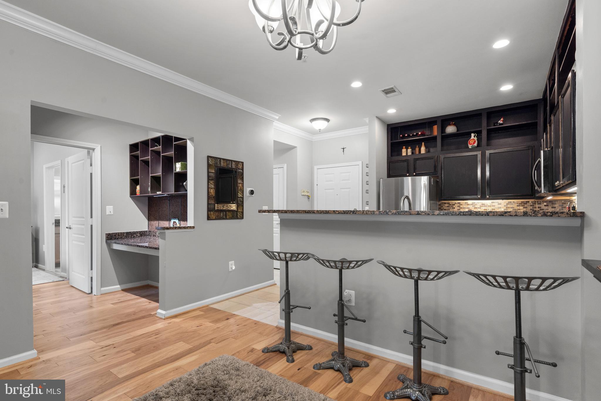 12000 Market Street, Unit 131 Reston, VA 20190 - Photo 13 of 41 a kitchen with granite countertop a refrigerator a stove a sink dishwasher and white cabinets with wooden floor