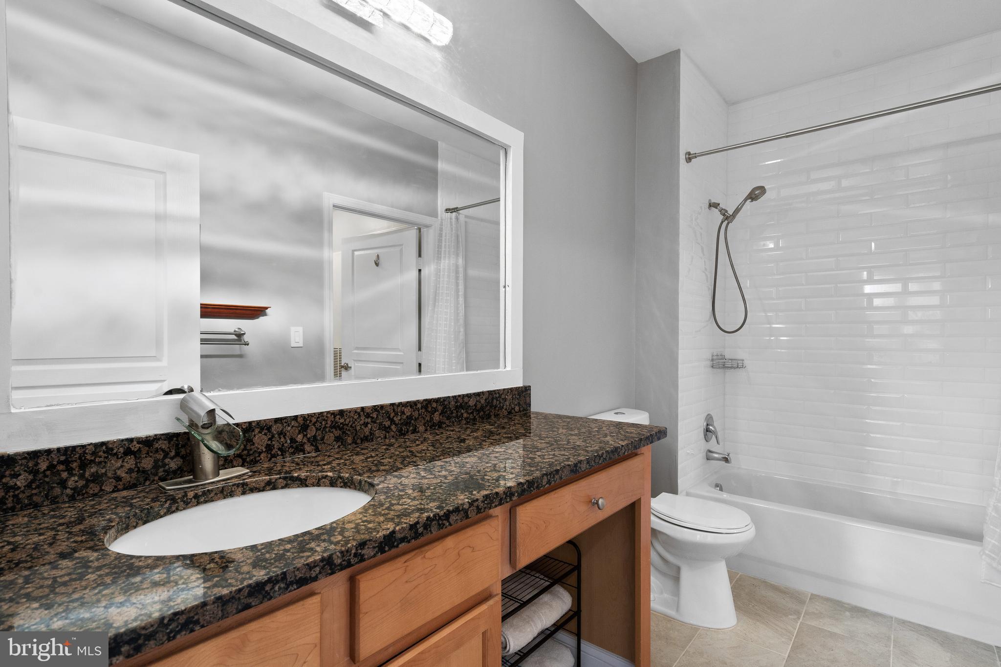 12000 Market Street, Unit 131 Reston, VA 20190 - Photo 30 of 41 a bathroom with a granite countertop sink toilet and shower
