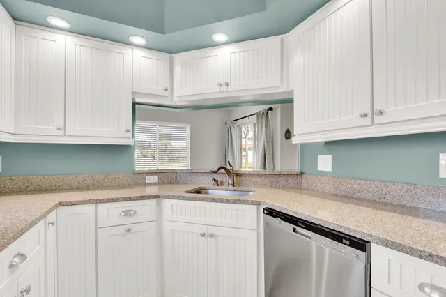 a kitchen with granite countertop white cabinets and a sink