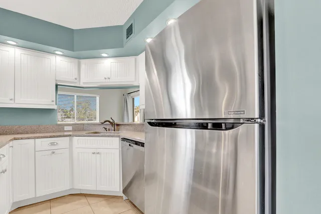 a kitchen with white cabinets and white refrigerator