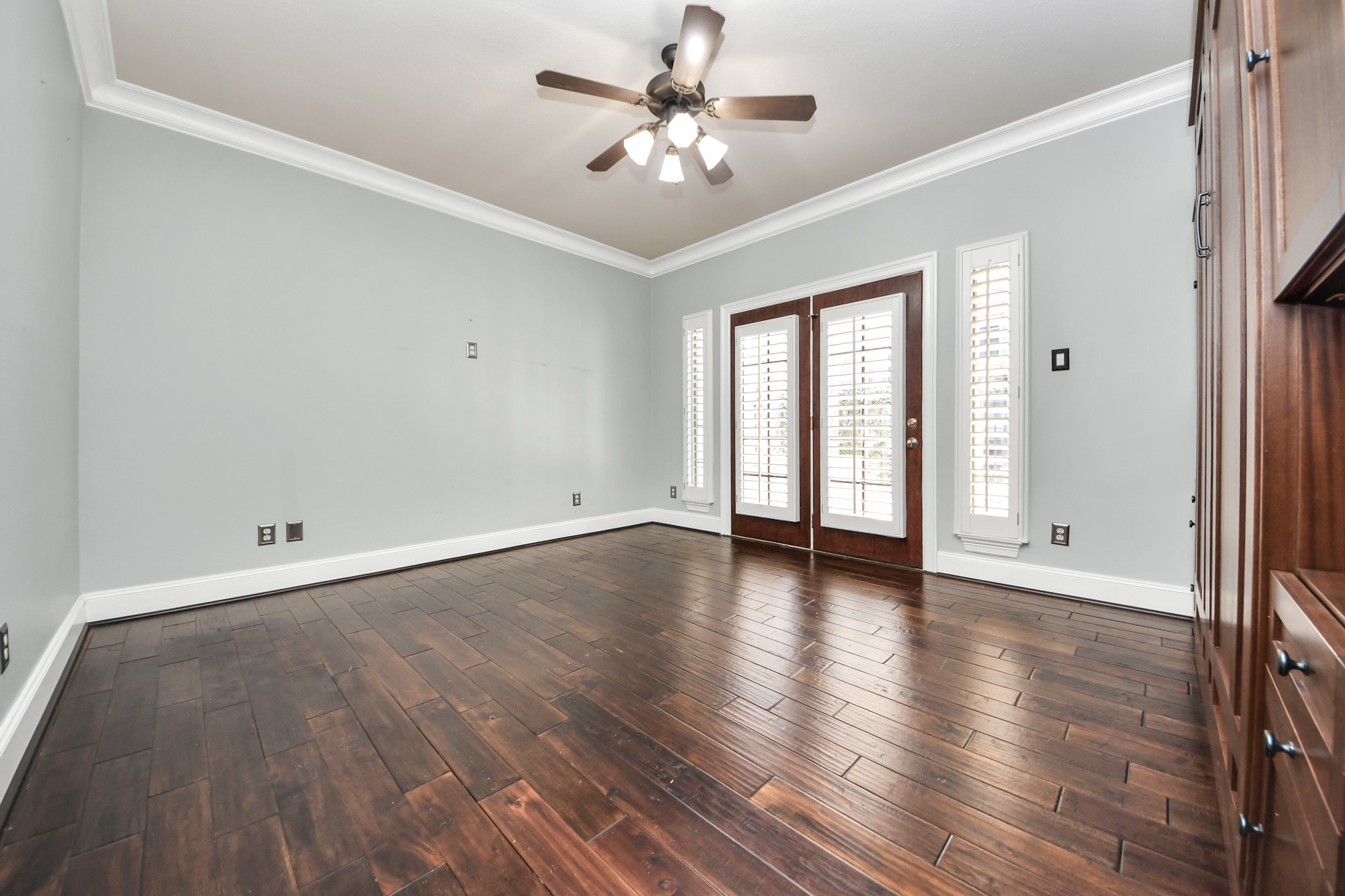 710 Jackson Hill Street Houston, TX 77007 - Photo 6 of 31 This room features dark hardwood floors, light gray walls, and white crown molding. It includes a ceiling fan above and glass doors with shutters leading outside to private patio.