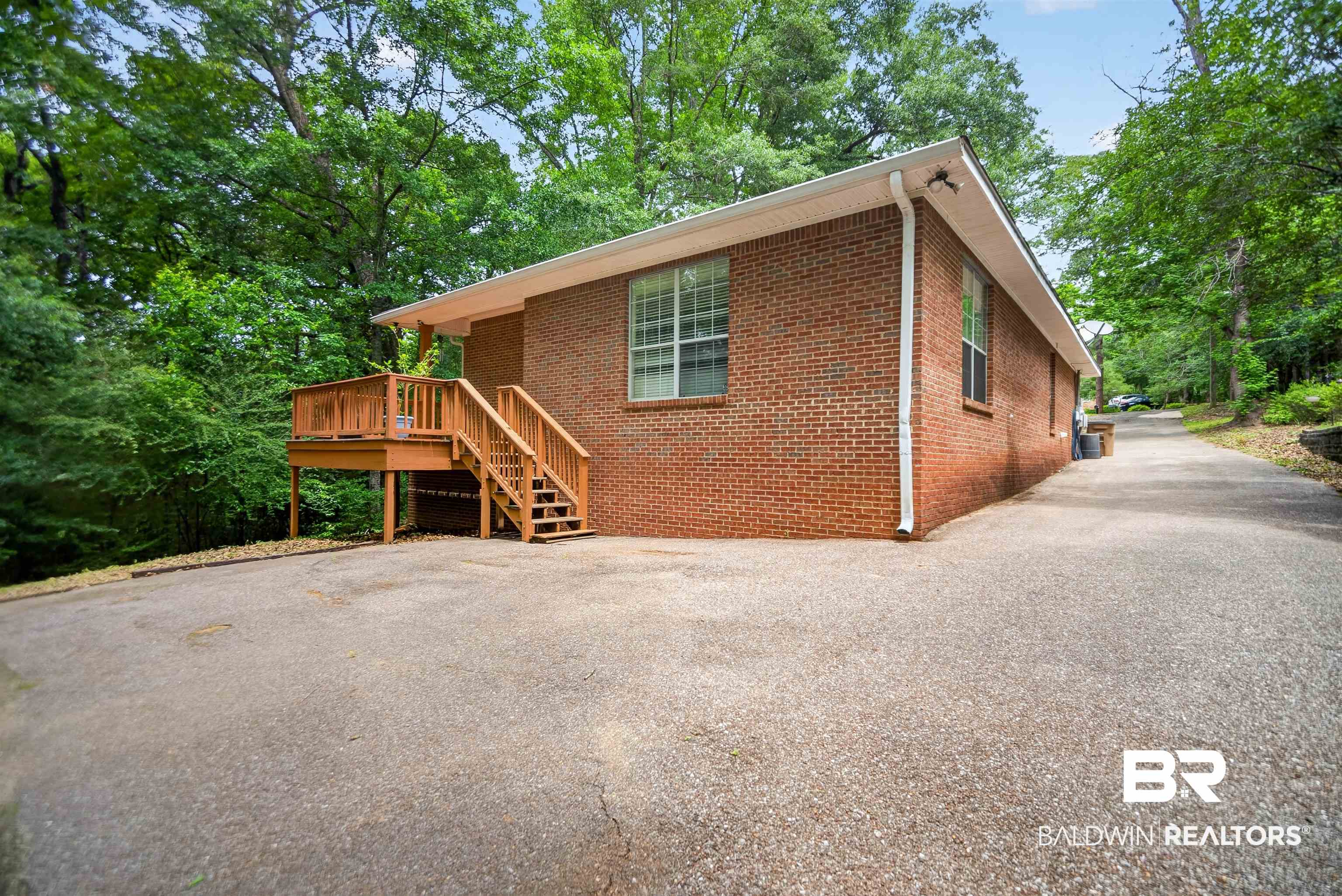 5913 Antoine Road Mobile, AL 36693 - Photo 28 of 33 Brick exterior featuring a wood deck with stairs and surrounding mature trees