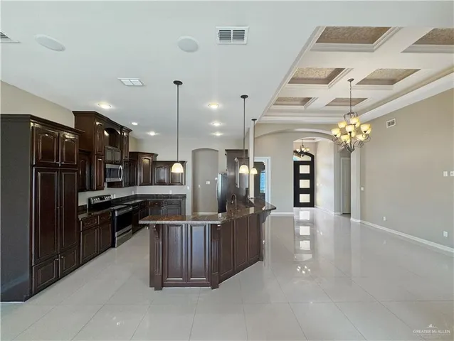 a kitchen with stainless steel appliances kitchen island granite countertop a refrigerator and a sink