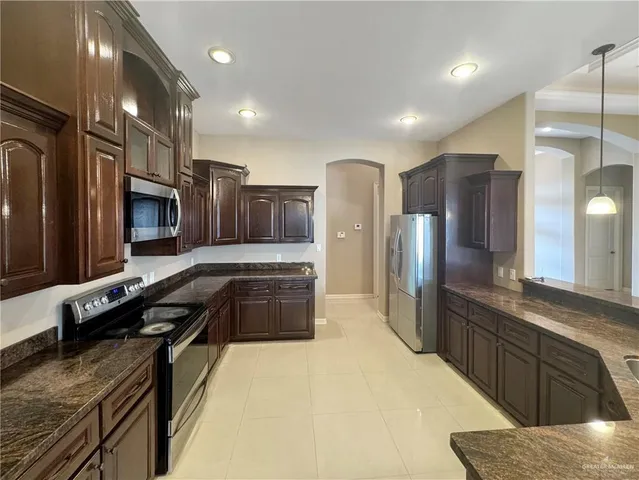 a large kitchen with a large counter top stainless steel appliances and cabinets