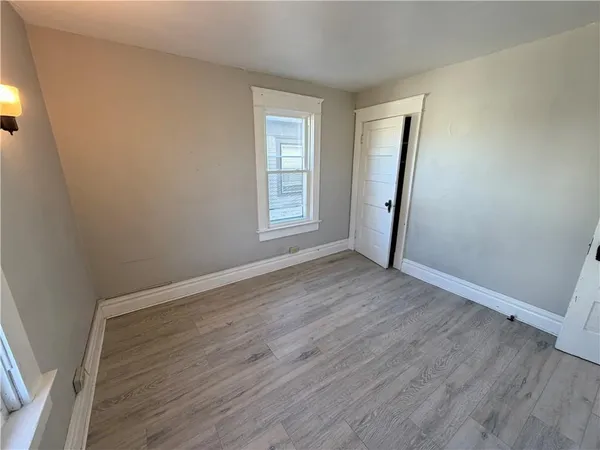 an empty room with wooden floor and window