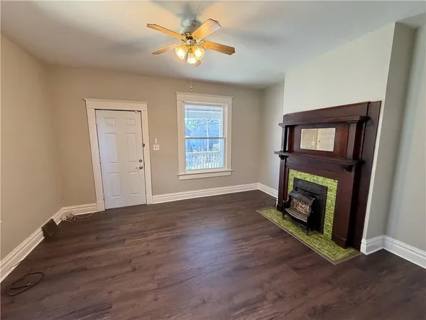 a view of an empty room with wooden floor fireplace and a window