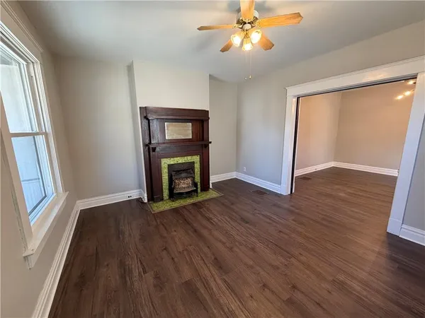 an empty room with wooden floor fan and windows