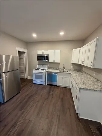 a kitchen with wooden floors appliances and cabinets