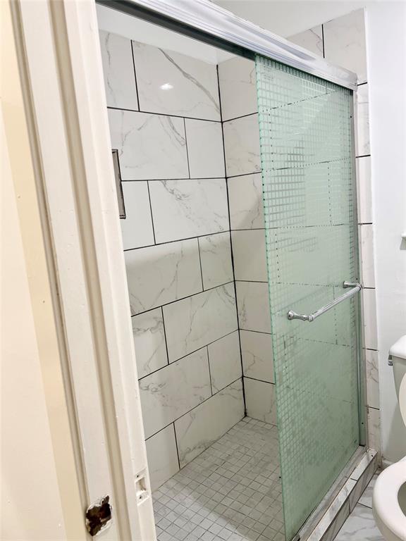 2529 Rutgers Drive Irving, TX 75062 - Photo 38 of 38 Shower enclosure featuring subway-tiled walls with dark grout, a small square-tiled floor, and a textured glass sliding door with chrome hardware