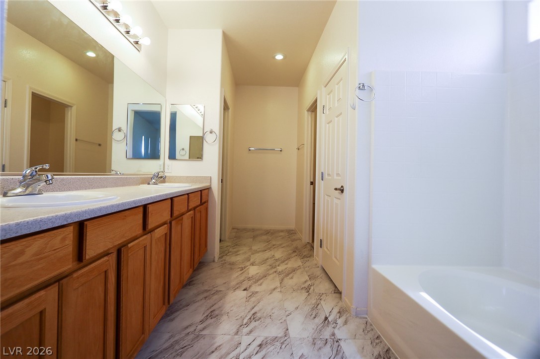 6472 Centennial Road Pahrump, NV 89048 - Photo 7 of 29 Double vanity sinks and tiled floors define this functional primary bathroom.