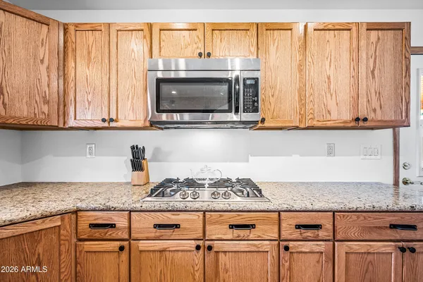 a kitchen with granite countertop a stove a microwave and white cabinets
