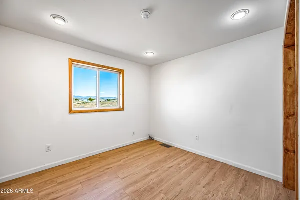 an empty room with wooden floor and window