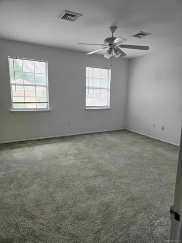 an empty room with a ceiling fan and windows
