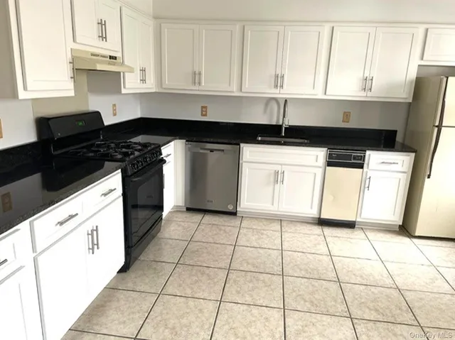 a kitchen with granite countertop a stove a sink and a microwave