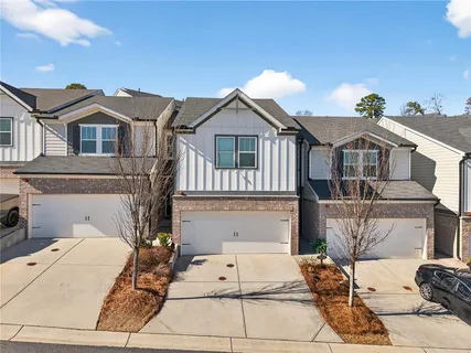 a view of a white house with large windows and a small yard
