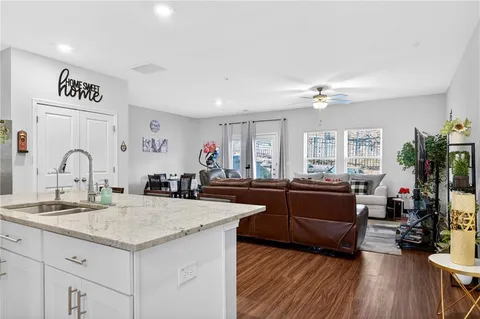 a large kitchen with granite countertop a stove a sink dishwasher and a dining table with wooden floor