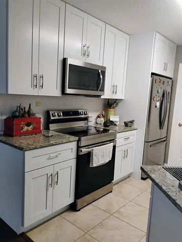 a kitchen with granite countertop stainless steel appliances a stove microwave and sink