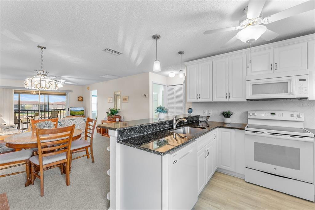 25100 Sandhill Boulevard, Unit R202 Punta Gorda, FL 33983 - Photo 3 of 39 a kitchen with a stove a chandelier and white cabinets