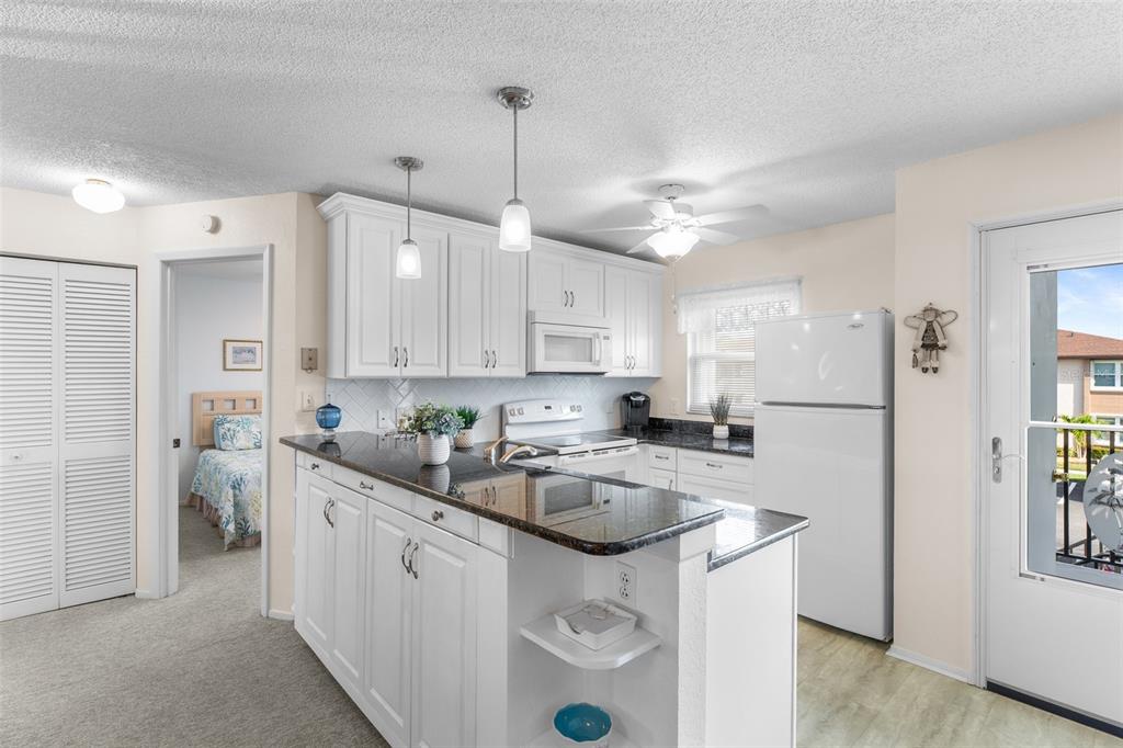 25100 Sandhill Boulevard, Unit R202 Punta Gorda, FL 33983 - Photo 5 of 39 a kitchen with a refrigerator a sink dishwasher a stove and white cabinets with wooden floor