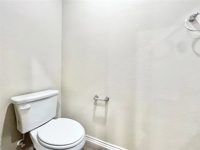 a white toilet sitting next to a white wall