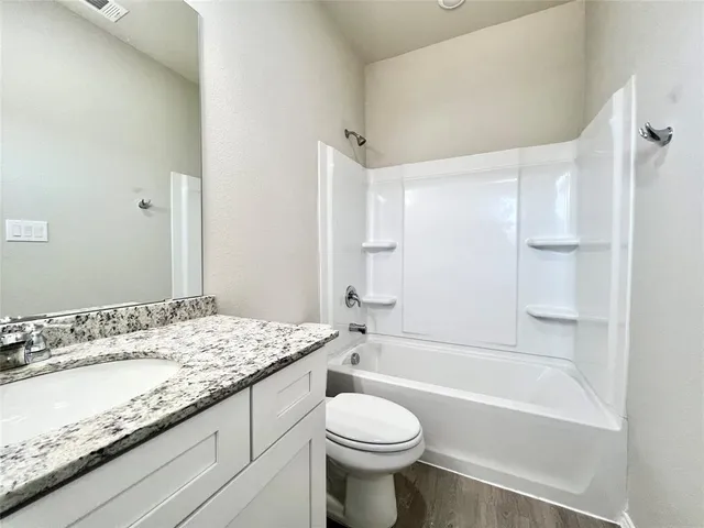 a bathroom with a granite countertop sink a toilet and shower