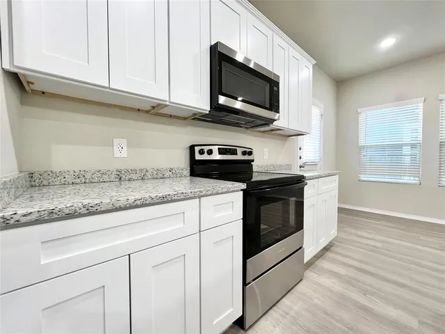 a kitchen with stainless steel appliances granite countertop white cabinets granite counter tops and a wooden floors