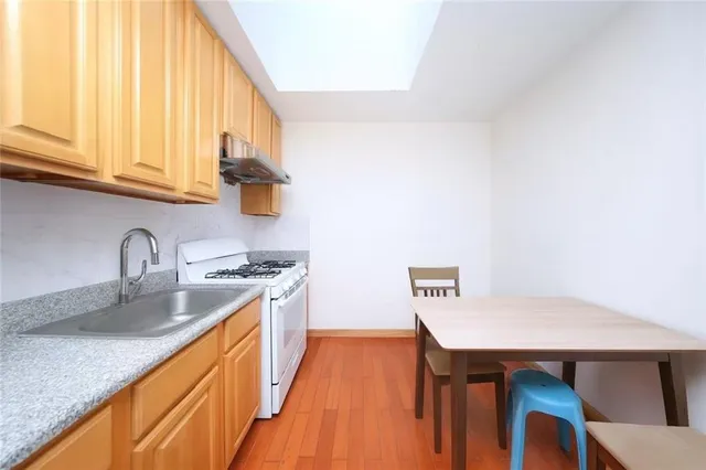 a kitchen with stainless steel appliances granite countertop a sink a stove and wooden floor